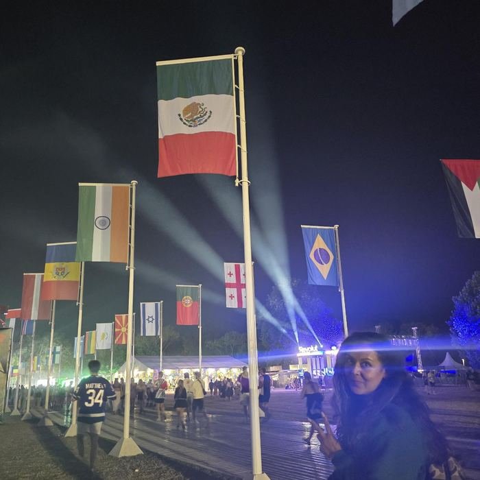 Viajera de TAIMX junto a la bandera de México en un festival internacional